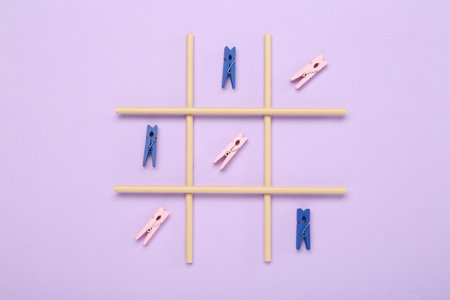 Tic tac toe game made with clothespins on lilac background, top viewの写真素材