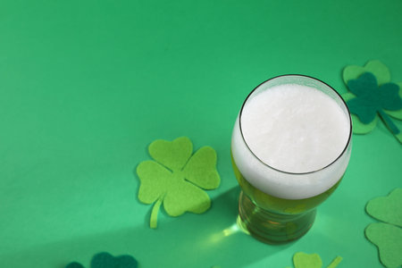 St. Patrick's day party. Green beer in glass and decorative clover leaves on green background, above view. Space for textの写真素材