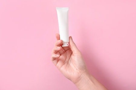 Woman with tube of hand cream on pink background, closeupの写真素材