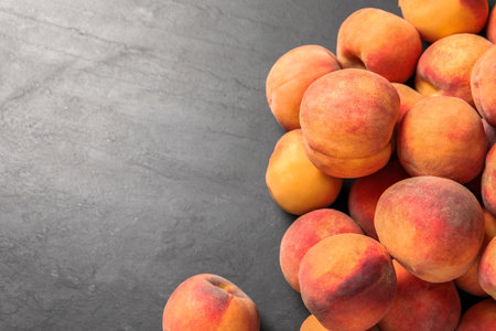 Fresh peaches on dark gray textured table, above view. Space for textの写真素材