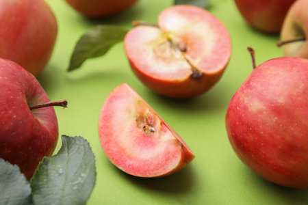 Tasty apples with red pulp and leaves on light green background, closeupの写真素材