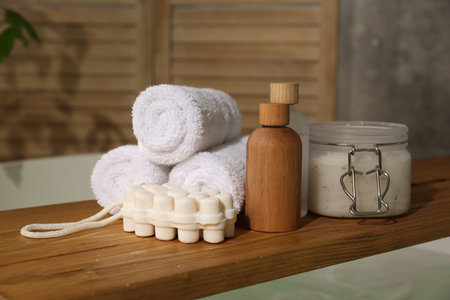 Wooden tray with spa products and towels on bath tub in bathroom