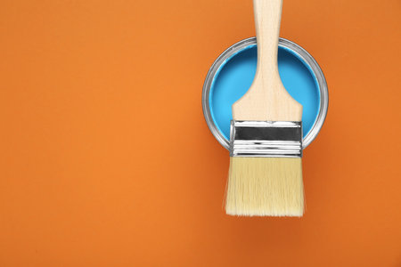 Can of light blue paint with brush on pale orange background, top view. Space for textの写真素材