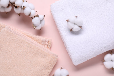 Cotton branch with fluffy flowers and terry towels on beige background, flat layの写真素材