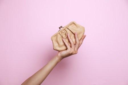 Woman holding leather purse on pink background, closeupの写真素材