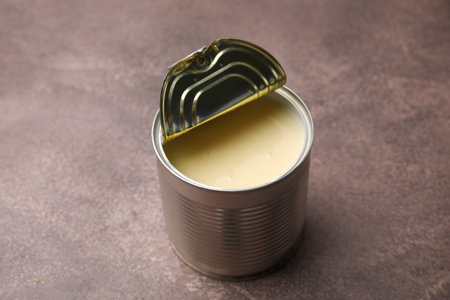 Open tin can with condensed milk on brown tableの写真素材