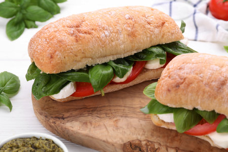 Delicious Caprese sandwiches with mozzarella, tomatoes and basil on white wooden table, closeupの写真素材