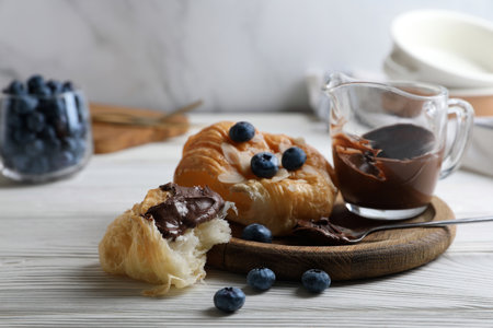 Delicious croissant with chocolate and blueberries on white wooden table, closeupの写真素材