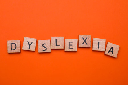 Wooden cubes with word Dyslexia on orange background, flat layの写真素材