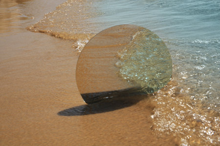 Round mirror reflecting sea on sandy beach. Space for textの写真素材