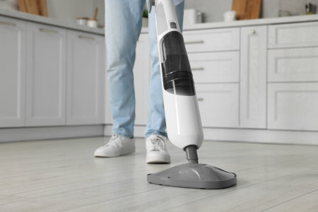 Man cleaning floor with steam mop at home, closeupの写真素材