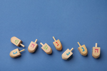 Wooden dreidels on blue background, flat lay with space for text. Traditional Hanukkah gameの写真素材