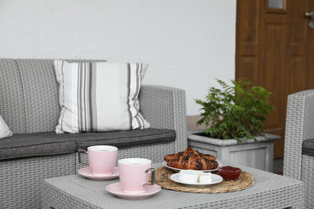 Outdoor breakfast with tea and croissants on rattan table on terraceの写真素材