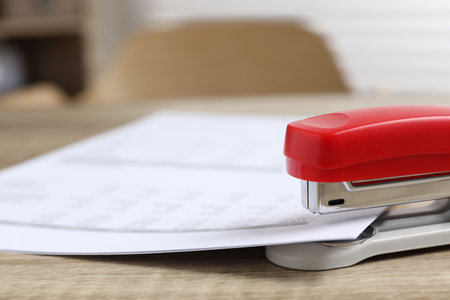 Bright stapler with documents on wooden table indoors, closeupの写真素材