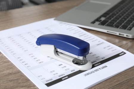 Bright stapler and document on wooden tableの写真素材