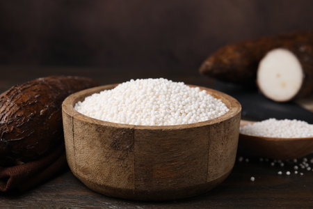 Tapioca pearls in bowl and cassava roots on wooden table, closeupの写真素材
