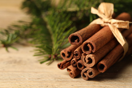 Bunch of cinnamon sticks and fir branches on wooden table, closeup. Space for textの写真素材