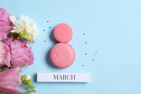 International Women's day. 8th of March made with delicious macarons and beautiful flowers on light...