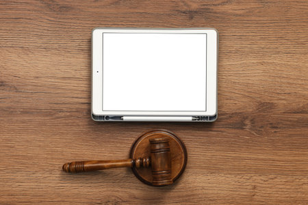 Modern tablet and gavel on wooden table, flat lay. Space for textの写真素材