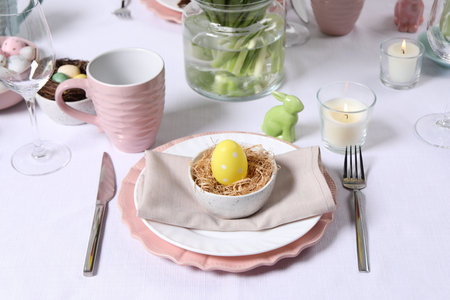 Festive table setting with painted egg in decorative nest. Easter celebration