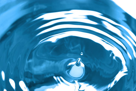 Splash of clear water with drops on blue background, closeupの写真素材