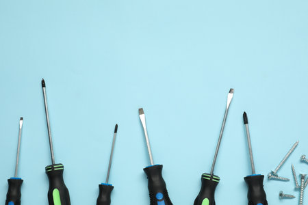 Set of screwdrivers and screws on light blue background, flat lay. Space for textの写真素材