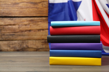 Learning foreign language. Different books on wooden table near flag of United Kingdom, space for textの写真素材