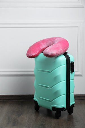 Pink travel pillow on turquoise suitcase indoorsの写真素材