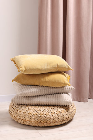 Soft pillows on wicker pouf in roomの写真素材