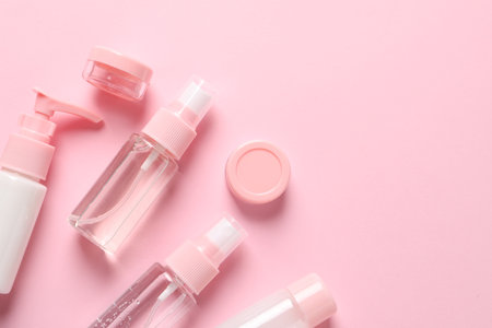 Cosmetic travel kit on pink background, flat lay. Space for textの写真素材