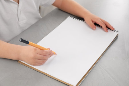 Little boy drawing with pencil at gray textured table, closeup. Child`s art