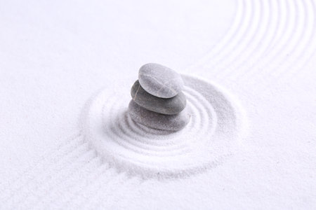 Zen garden stones on white sand with pattern