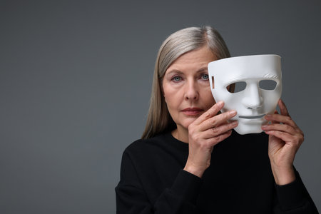 Multiple personality concept. Woman with mask on gray background, space for text