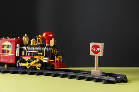 Road Stop sign as barrier blocking way for toy train on yellow surface, closeup. Development through obstacles overcomingの写真素材