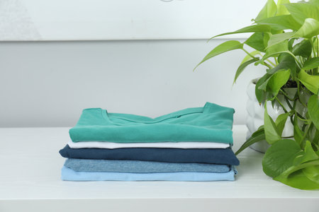 Sorting and organizing. Stack of different folded clothes on white table indoors