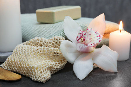 Composition with different spa products and orchid flower on gray table, closeup