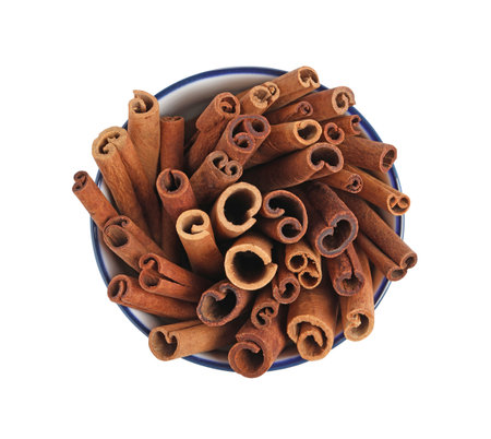 Cinnamon sticks in bowl isolated on white, top viewの写真素材