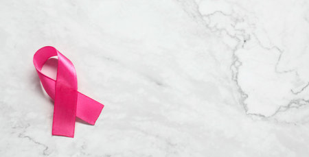 Pink ribbon on white marble table, top view and space for text. Breast cancer awarenessの写真素材