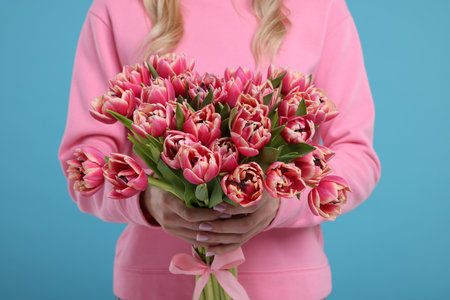 Woman holding beautiful bouquet on light blue background, closeupの写真素材