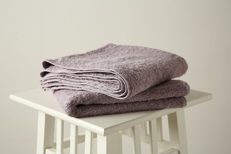 Violet towels on stool against white wall, closeupの写真素材