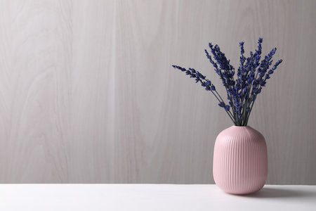 Bouquet of beautiful preserved lavender flowers on white table near gray wooden wall, space for textの写真素材