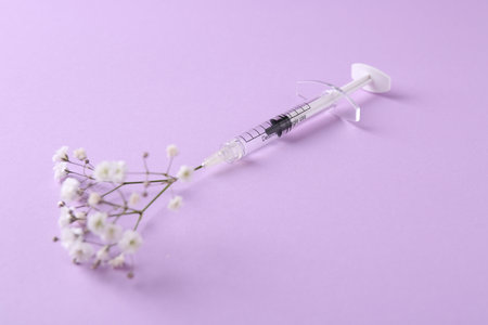 Cosmetology. Medical syringe and gypsophila on violet backgroundの写真素材