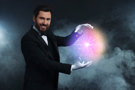 Magic and sorcery. Magician with fantastic light in smoke on dark background
