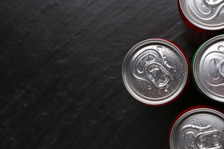 Energy drink in wet cans on black textured background, top view. Space for textの写真素材