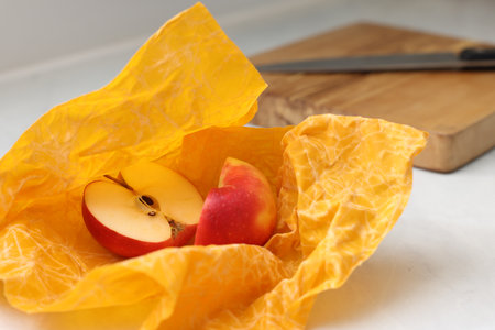 Halves of apple with orange beeswax food wrap on table, closeupの写真素材