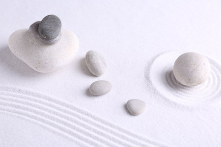 Zen garden stones on white sand with pattern, flat layの写真素材