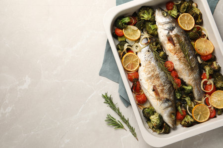 Delicious fish with vegetables and lemon in baking dish on light marble table, top view. Space for textの写真素材