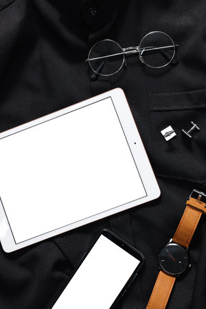 Modern tablet, smartphone, watch and glasses on black shirt, top view. Space for textの写真素材