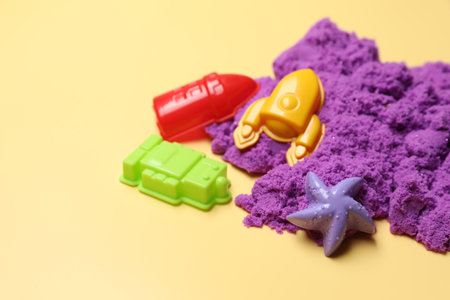 Violet kinetic sand and plastic toys on beige background, space for textの写真素材