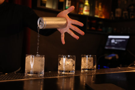Bartender pouring energy drink into glass at counter in bar, closeupの写真素材
